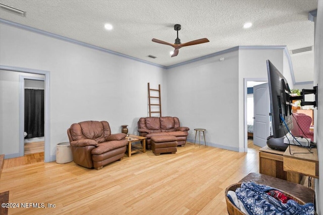 living room featuring ceiling fan, wood-type flooring, a textured ceiling, and ornamental molding