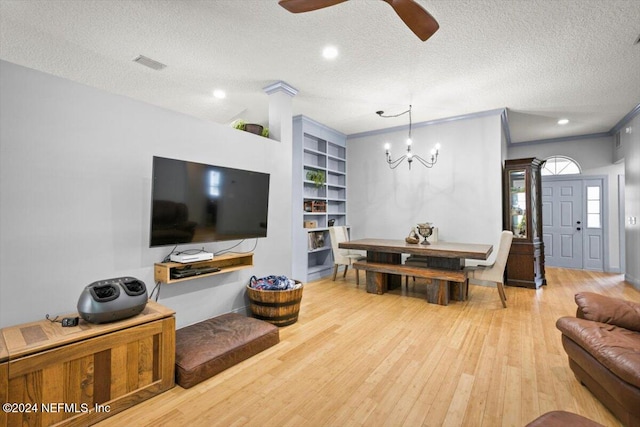 living room with built in shelves, crown molding, hardwood / wood-style floors, a textured ceiling, and ceiling fan with notable chandelier