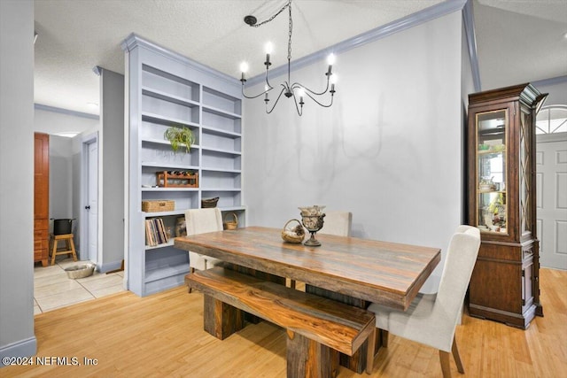 dining area with light hardwood / wood-style floors, ornamental molding, a textured ceiling, and a chandelier