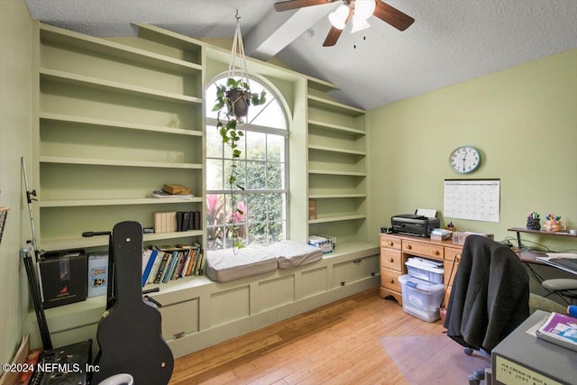 office area featuring vaulted ceiling with beams, ceiling fan with notable chandelier, light wood-type flooring, and a textured ceiling