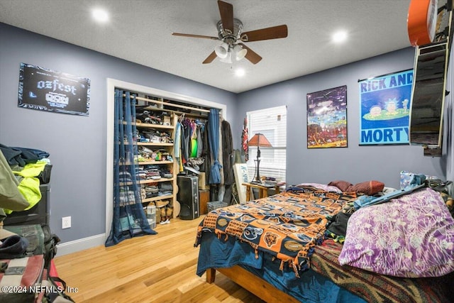 bedroom with ceiling fan, a closet, wood-type flooring, and a textured ceiling