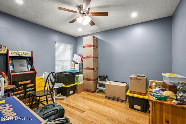 game room with a textured ceiling, light hardwood / wood-style floors, and ceiling fan