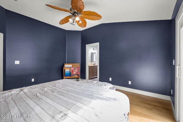 bedroom with ceiling fan, ensuite bathroom, a textured ceiling, vaulted ceiling, and hardwood / wood-style flooring