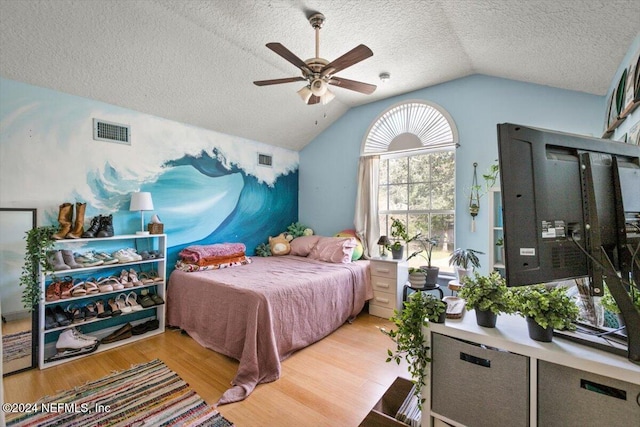 bedroom featuring ceiling fan, vaulted ceiling, a textured ceiling, and light hardwood / wood-style flooring