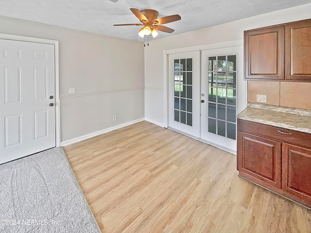 interior space featuring light wood-type flooring, french doors, ceiling fan, and a textured ceiling