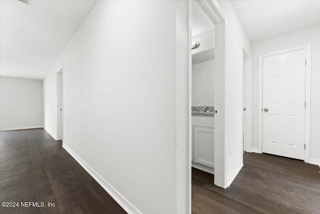 corridor with dark hardwood / wood-style floors and a textured ceiling