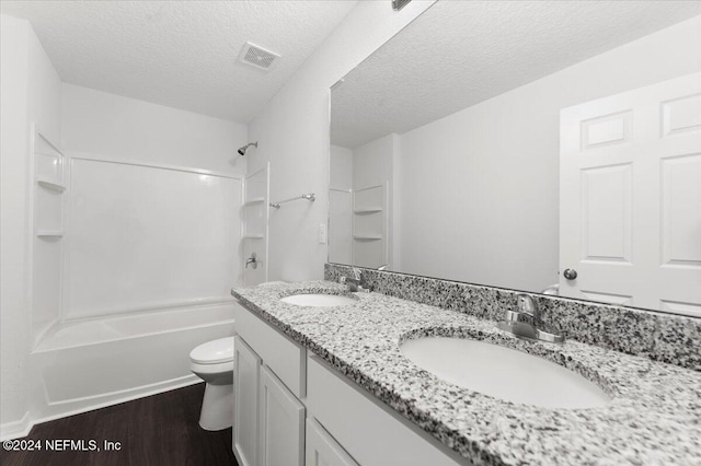 full bathroom with wood-type flooring, toilet, a textured ceiling, shower / bathing tub combination, and vanity