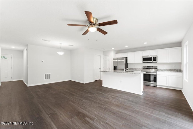 kitchen featuring dark wood-type flooring, a center island with sink, white cabinets, hanging light fixtures, and appliances with stainless steel finishes