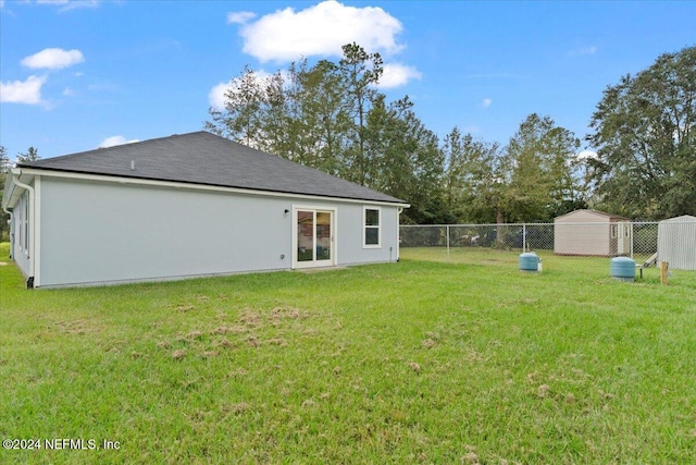 rear view of property with a storage unit and a lawn