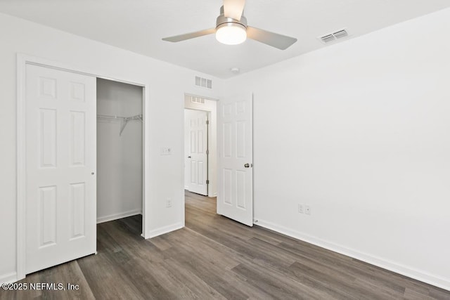 unfurnished bedroom featuring dark wood-type flooring, a closet, and ceiling fan