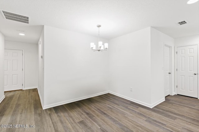 unfurnished room with dark hardwood / wood-style floors and an inviting chandelier