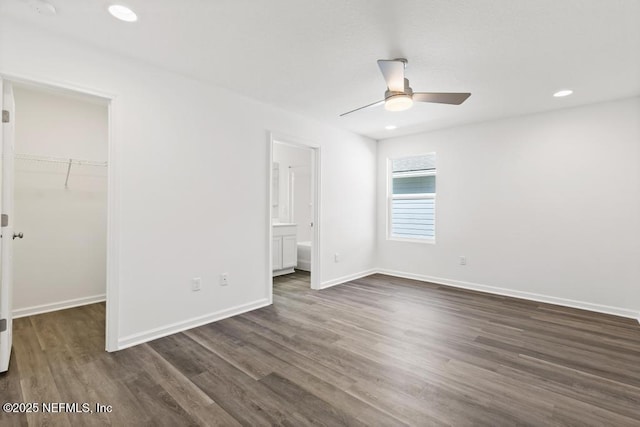 unfurnished bedroom featuring ensuite bathroom, a walk in closet, dark hardwood / wood-style flooring, a closet, and ceiling fan