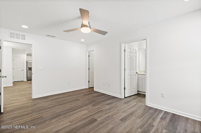 unfurnished bedroom featuring ceiling fan, stainless steel fridge, dark hardwood / wood-style flooring, and ensuite bath