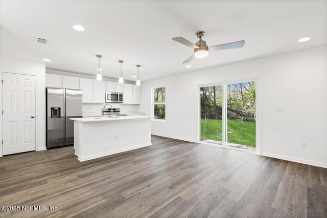 kitchen featuring white cabinetry, dark hardwood / wood-style floors, an island with sink, pendant lighting, and stainless steel appliances