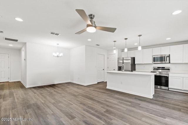 kitchen with stainless steel appliances, decorative light fixtures, a center island, and white cabinets