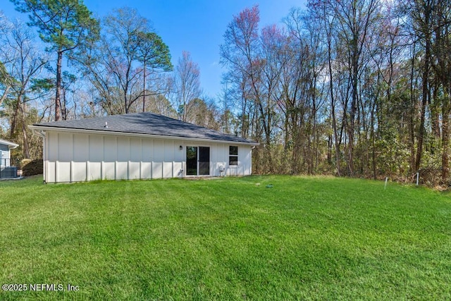 back of house featuring central air condition unit and a lawn