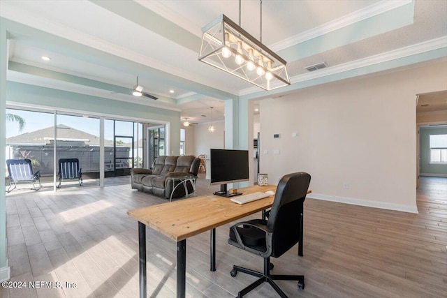 office area with wood-type flooring, a raised ceiling, a wealth of natural light, and crown molding