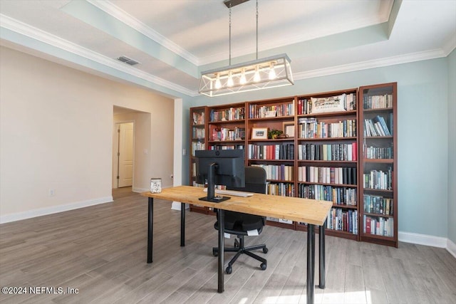 office space with a tray ceiling, wood-type flooring, and ornamental molding