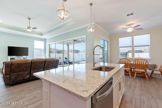 kitchen with stainless steel dishwasher, pendant lighting, a center island with sink, light hardwood / wood-style flooring, and white cabinetry