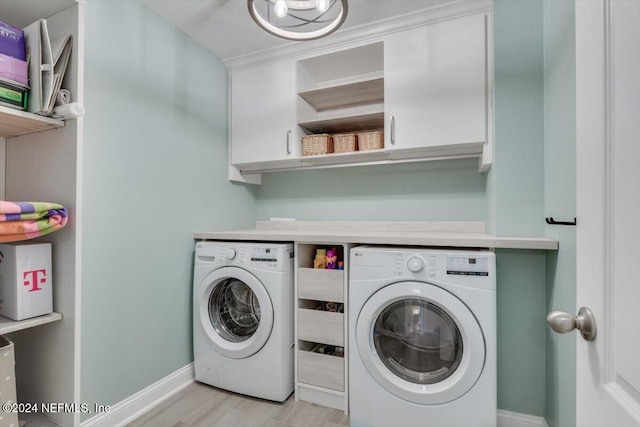 laundry area featuring washing machine and dryer, cabinets, and light hardwood / wood-style floors