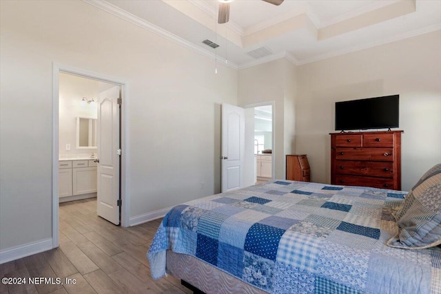 bedroom featuring connected bathroom, light hardwood / wood-style floors, ceiling fan, and crown molding