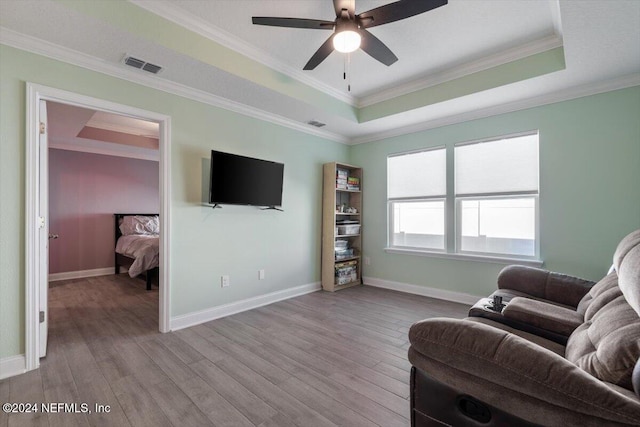 living room featuring light hardwood / wood-style floors, a raised ceiling, and crown molding