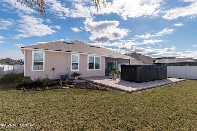 rear view of property with a yard, a patio, and a hot tub