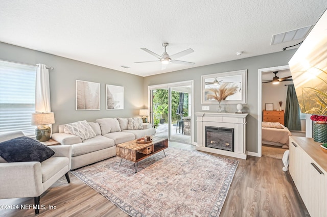 living room featuring a textured ceiling, hardwood / wood-style flooring, and ceiling fan