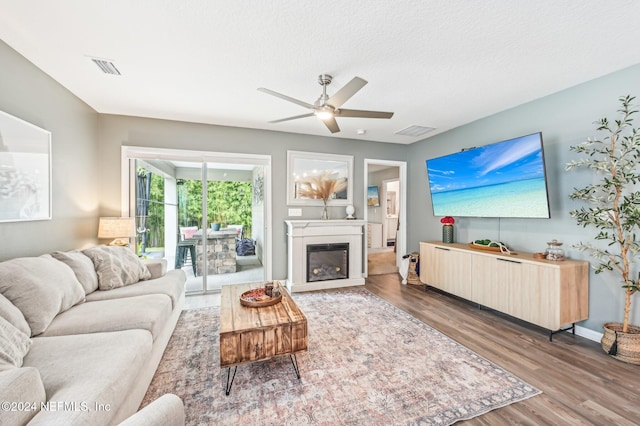 living room featuring ceiling fan, dark hardwood / wood-style floors, and a textured ceiling