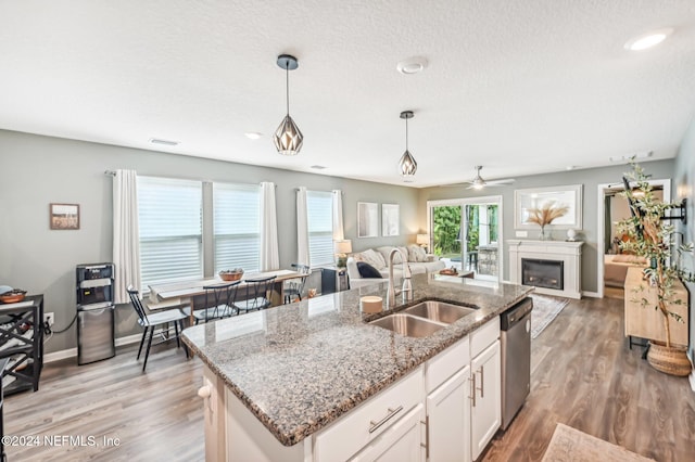 kitchen with light hardwood / wood-style floors, dishwasher, hanging light fixtures, sink, and white cabinetry