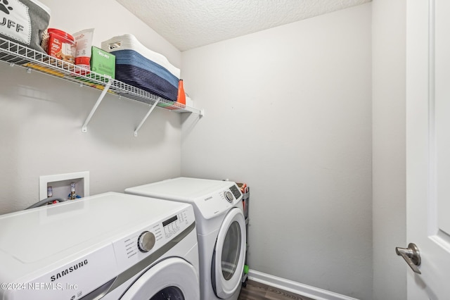 laundry room featuring washing machine and dryer, a textured ceiling, and wood-type flooring