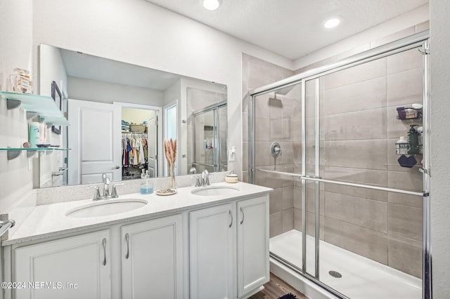 bathroom with hardwood / wood-style floors, vanity, an enclosed shower, and a textured ceiling