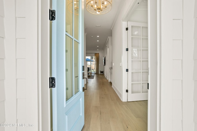 corridor with baseboards, ornamental molding, light wood-type flooring, a chandelier, and recessed lighting