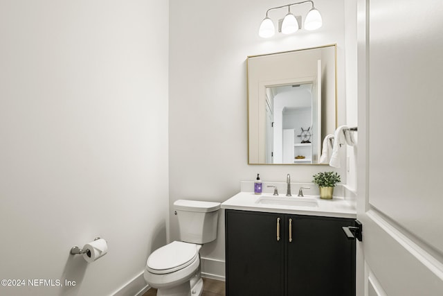 half bathroom with toilet, baseboards, wood finished floors, and vanity