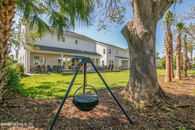 rear view of property featuring a patio area, fence, a playground, and a yard