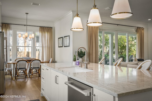 kitchen with light wood-style flooring, a sink, ornamental molding, appliances with stainless steel finishes, and an island with sink