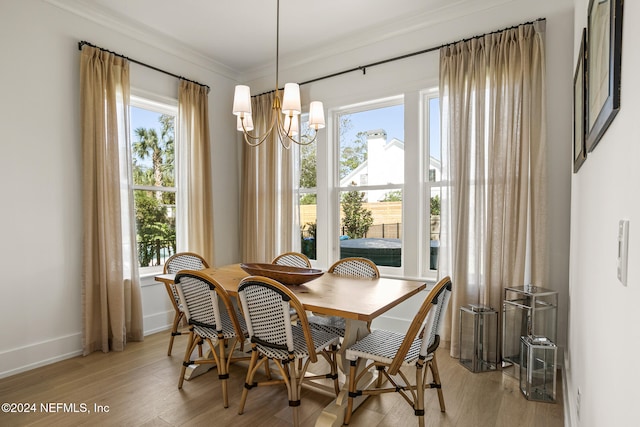 dining room with a chandelier, baseboards, light wood-style flooring, and crown molding