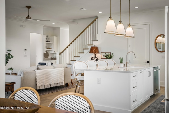 kitchen with white cabinets, dark wood-style floors, ceiling fan, ornamental molding, and light stone counters