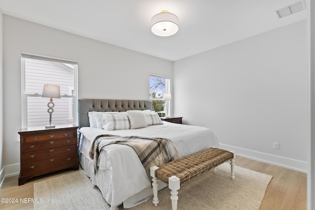 bedroom featuring light wood-type flooring, visible vents, and baseboards