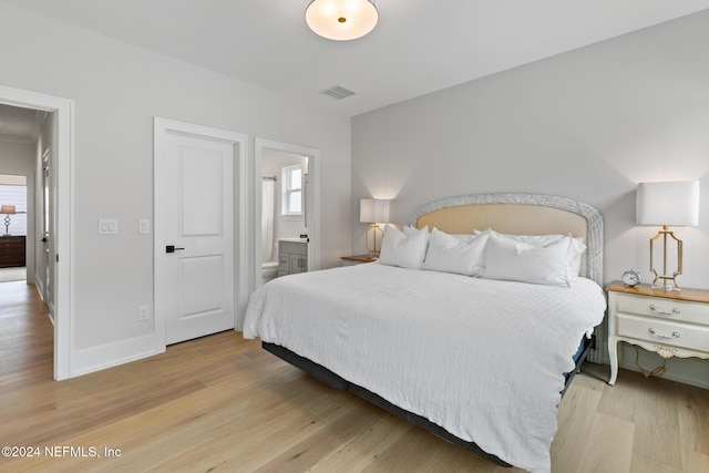 bedroom featuring baseboards, visible vents, wood finished floors, and ensuite bathroom