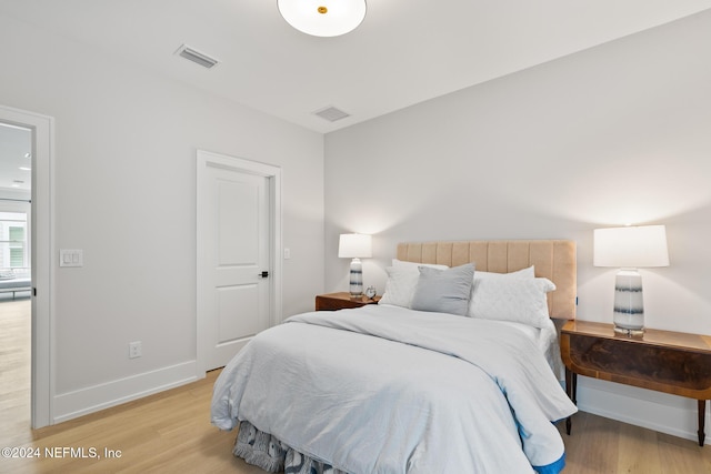 bedroom with light wood-style floors, visible vents, and baseboards