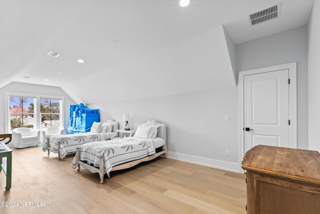 bedroom with lofted ceiling, light wood-style flooring, and visible vents