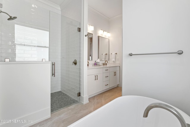 bathroom with a soaking tub, a shower stall, ornamental molding, and vanity