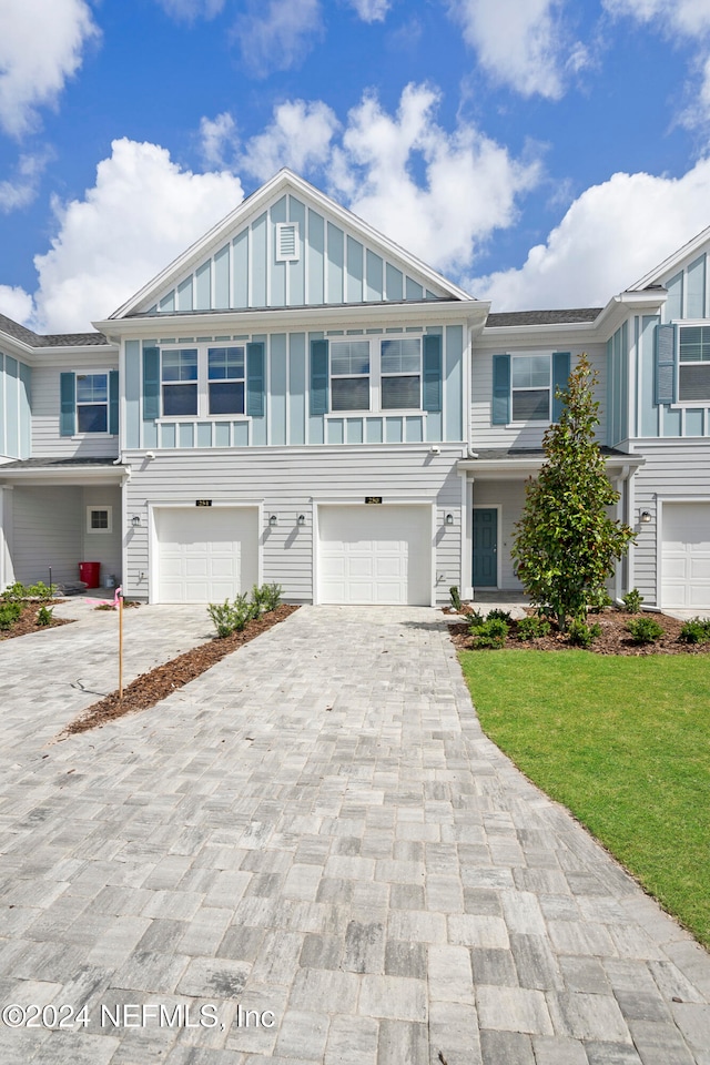 townhome / multi-family property with a front lawn and a garage