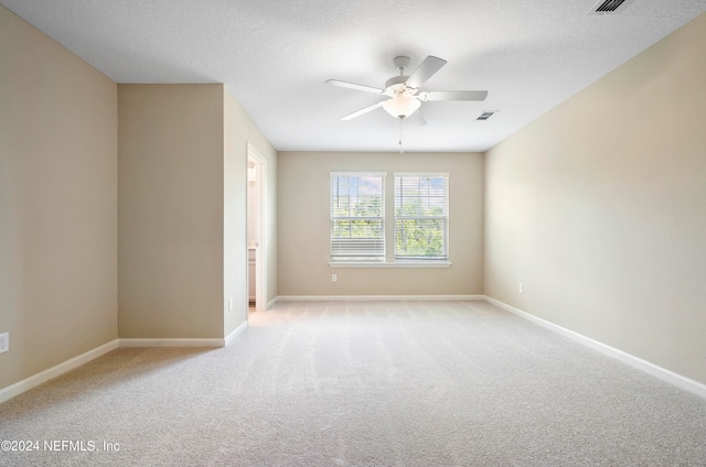 carpeted spare room featuring ceiling fan and a textured ceiling