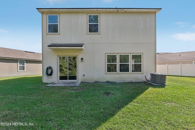 back of property featuring central air condition unit and a yard