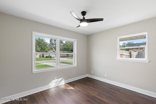 empty room featuring a wealth of natural light, ceiling fan, and dark wood-type flooring