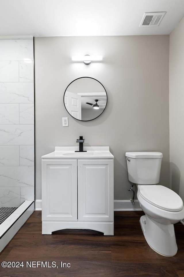 bathroom with a tile shower, toilet, vanity, and hardwood / wood-style flooring