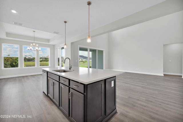 kitchen featuring light hardwood / wood-style floors, sink, an island with sink, stainless steel dishwasher, and hanging light fixtures