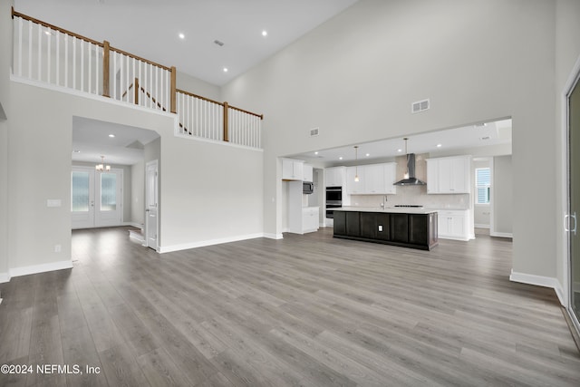 unfurnished living room featuring wood-type flooring, french doors, and a towering ceiling